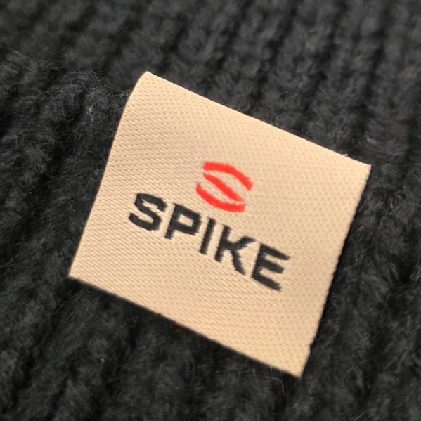 Close-up of a woven clip label sewn onto a black knit beanie