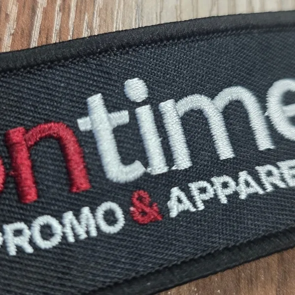 Close-up of an embroidered patch with red and white lettering and a black border