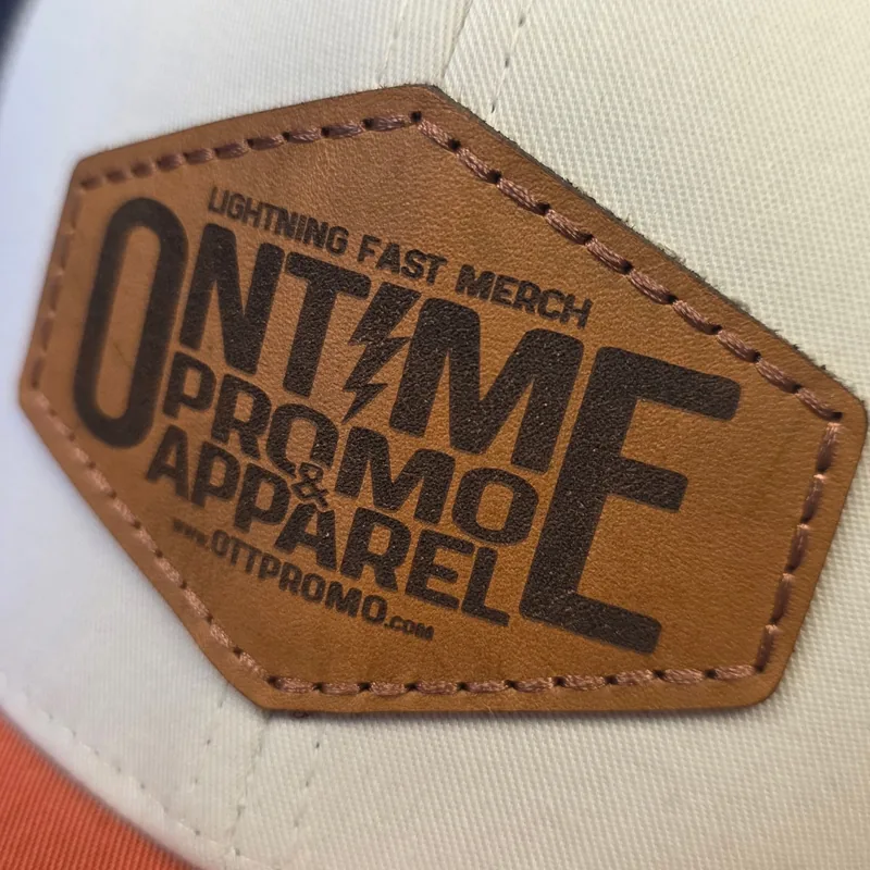 Close-up of a laser-etched hexagon leather patch with stitched edges on a cream trucker hat