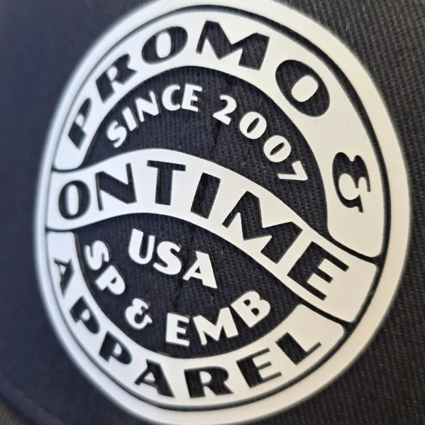Close-up of a raised white silicone transfer badge on a black cap