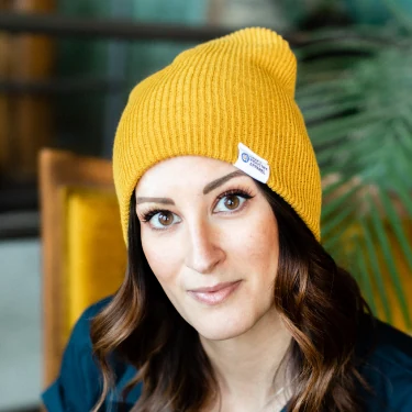 Woman wearing a yellow knit beanie with a Craft Industry Apparel label