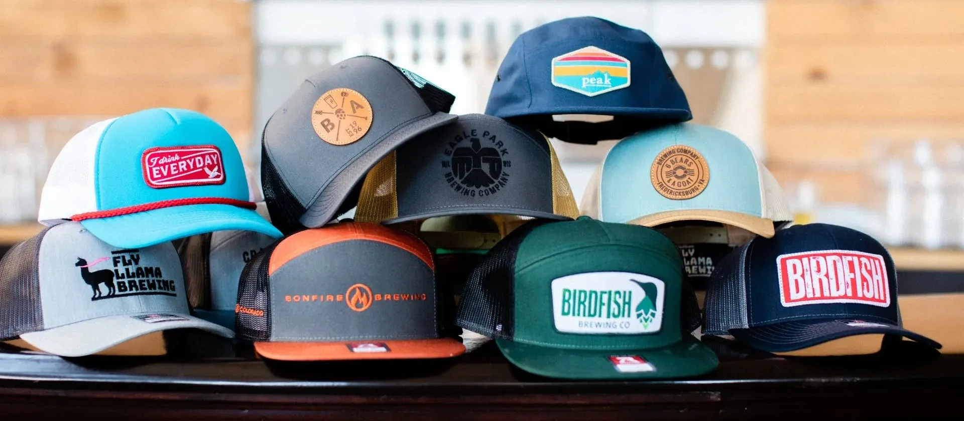 Display of custom-decorated trucker and snapback hats with leather, woven and embroidered patches